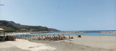 a beach with chairs and umbrellas and the ocean at Metoxaki in Dhaskalianá