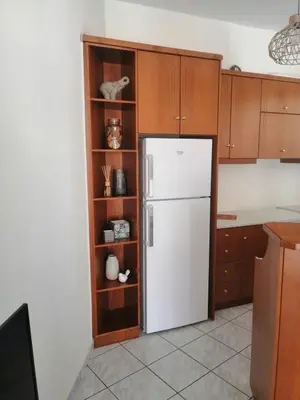 a kitchen with a white refrigerator and wooden cabinets at Aria Aparment in Palaiochóra