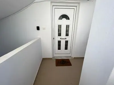 a staircase with a white door and a sign on the floor at Aria Aparment in Palaiochóra