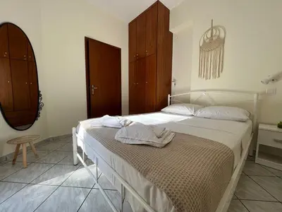 a bedroom with a bed with white sheets and wooden cabinets at Aria Aparment in Palaiochóra