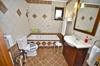 a bathroom with a tub and a toilet and a sink at Fotini Traditional Villas in Kavoúsion