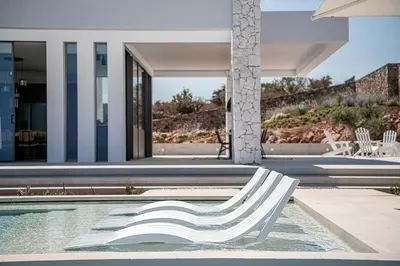 a white chair sitting next to a swimming pool at Nature & Beauty Villa in Xirostérnion