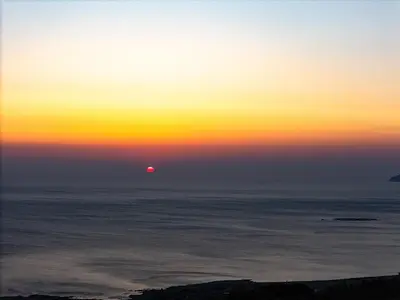 a sunset over the ocean with the sun in the horizon at Mouria Luxury Suites - Adults Only in Falasarna