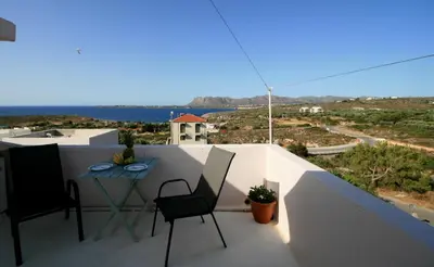 a patio with a table and chairs on a balcony at Cozy SeaView Apartment Walking Distance to Beach in Akhatzikiá