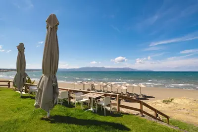 a beach with umbrellas and chairs and the ocean at Elia Agia Marina Hotel in Agia Marina Nea Kydonias
