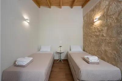 two beds in a room with a stone wall at Lithos Residence in Chania Town