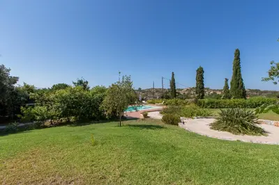 a garden with a swimming pool and trees and grass at Ellie Villa in Tersanas