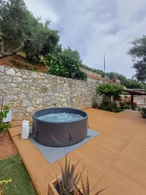 a hot tub in a garden with a stone wall at Olive Stone in Kamisianá