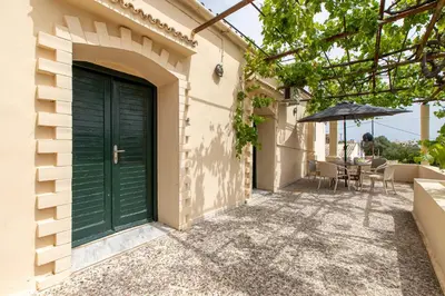 a green door on the side of a building with an umbrella at The Orestis Old Cottage House in Stalos