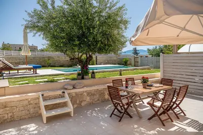 a patio with a table and chairs and an umbrella at Villa Crista in Áptera