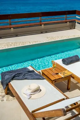 a hat sitting on a table next to a swimming pool at Kormoranos-Hydrobates Waterfront Villa in Chania Town