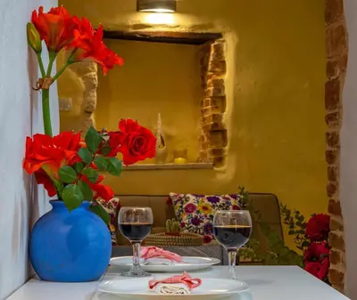 a table with two glasses of wine and a vase with red flowers at Mythos -Old Town-Old harbour Chania in Chania Town