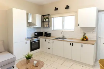 a kitchen with white cabinets and a table at kolymvari4you in Kolymvari
