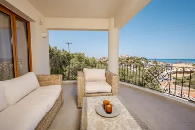 a living room with a couch and a chair on a balcony at Zen Maisonette Retreat in Daratso