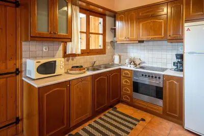 a kitchen with wooden cabinets and a microwave at Mountain View Villa, by the Pool,Aris in Próvarma