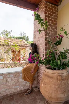 a woman sitting on a brick wall next to a potted plant at Mountain View Villa, by the Pool,Aris in Próvarma