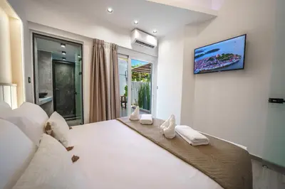 a bedroom with a large white bed with a tv on the wall at OLYMPIA Luxury Apartment in Chania Town
