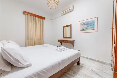 a white bedroom with a bed and a mirror at Lyria Hotel Apartments in Stalos