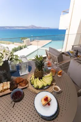 a table with a plate of food and a plate of fruit at Kymvari - Stunning sea view-elegant apt-infinity shared pool in Kalyves