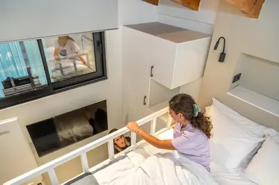 a girl is sitting on a bed in a room at The Nest in Chania Town