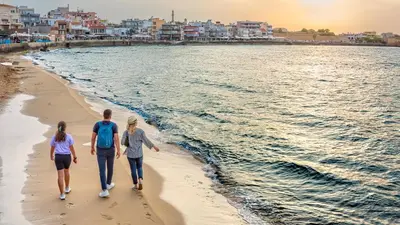 a group of three people walking on the beach at The Nest in Chania Town