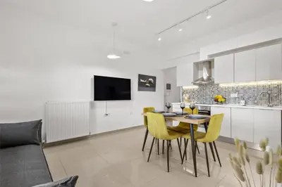a kitchen and dining room with a table and yellow chairs at Palea Luxury Living in Galatás