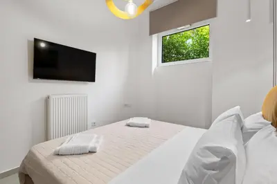 a white bedroom with a bed and a flat screen tv at Palea Luxury Living in Galatás
