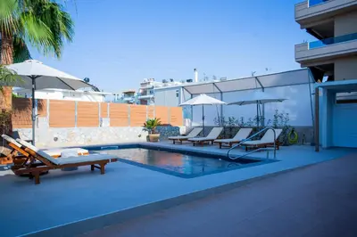 a swimming pool with lounge chairs and umbrellas at Be Crete - Villa Del Sol in Chania Town