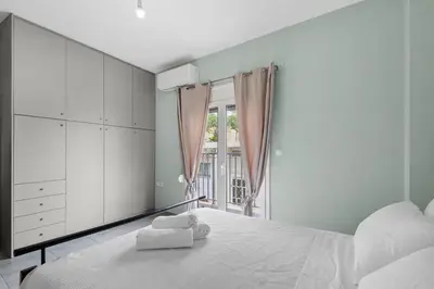 a white bedroom with a large bed and a window at Litsa's Maisonette Near Sea - City Center in Chania Town