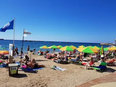 a crowd of people sitting on a beach with umbrellas at Litsa's Maisonette Near Sea - City Center in Chania Town