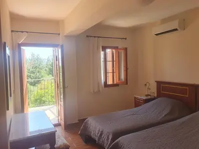 a bedroom with two beds and a sliding glass door at Villa Eudokia Terrace Views Pool in Douliana