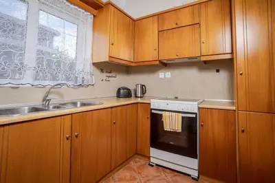 a kitchen with wooden cabinets and a sink and a stove at Sellianos Apartment In Kalyves -BY APOKORONAS VILLAS in Kalyves