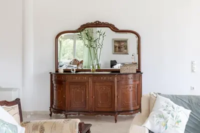 a mirror on top of a wooden dresser in a living room at Olive Ηouse, Quiet, Cozy, mountain view, family in Milonianá