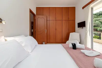 a bedroom with a large white bed and a window at Olive Ηouse, Quiet, Cozy, mountain view, family in Milonianá