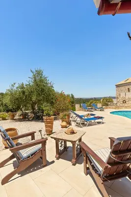 a patio with a table and chairs and a pool at Villa Calista In Aspro -BY APOKORONAS VILLAS in Koprána