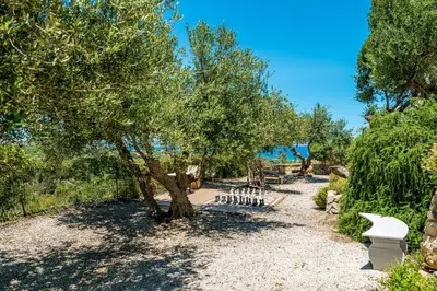 a park with a tree and benches in the sand at Villa Calista In Aspro -BY APOKORONAS VILLAS in Koprána