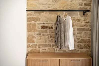a room with a stone wall and a wooden dresser at Petra Retreat Residence in Daratso