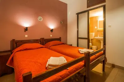 a bedroom with a bed with orange sheets and a mirror at Savas Rooms in Palaiochóra