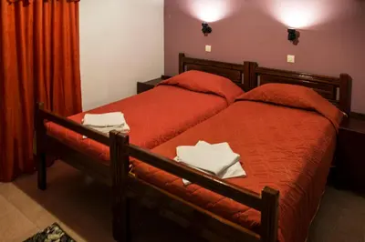 a bedroom with two beds with red sheets at Savas Rooms in Palaiochóra