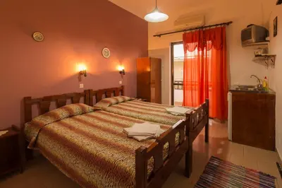 a bedroom with a large bed and a kitchen at Savas Rooms in Palaiochóra