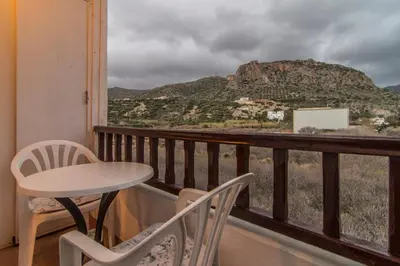 a balcony with a table and chairs and a mountain at Savas Rooms in Palaiochóra