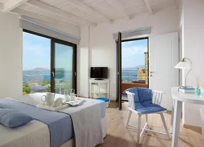 a white bedroom with a bed and a table and chair at Villa Niolos I in Marathi