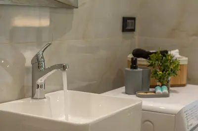 a bathroom with a sink and a washing machine at Liastera Luxury Apartments in Áyios Fótios