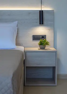 a bed with a nightstand with a plant on it at Liastera Luxury Apartments in Áyios Fótios