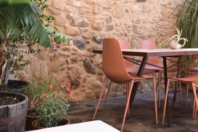 a table and chairs in front of a stone wall at Mozaik House