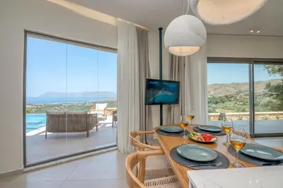 a dining room with a table and a view of the ocean at Villa Tierra in Kissamos