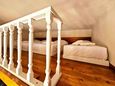 two beds in a room with white walls and wood floors at BROWN ON GREEN a stone house with amazing view in Drapaniás