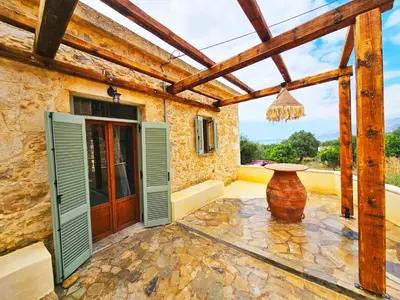 a patio with a wooden door and a large vase at BROWN ON GREEN a stone house with amazing view in Drapaniás