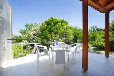 a white table and white chairs on a balcony at Galatas Maisonette in Galatás
