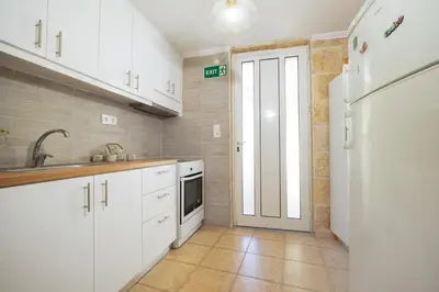 a kitchen with white cabinets and a white refrigerator at Galatas Maisonette in Galatás